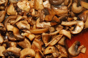 Fried champignon mushrooms in a pan closeup background texture