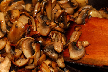 Fried champignon mushrooms in a pan closeup background texture