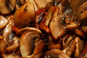 Fried champignon mushrooms in a pan closeup background texture