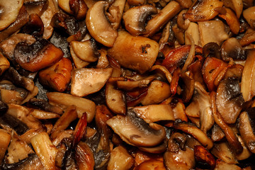 Fried champignon mushrooms in a pan closeup background texture