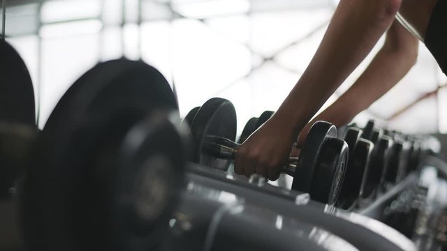 Female hands finishing weight training in fitness club.