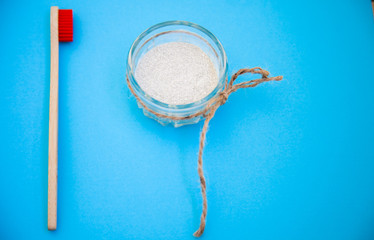 one toothbrushes, tooth powder on a blue wooden background. Minimalism, hygiene of the mouth cavity. View from above