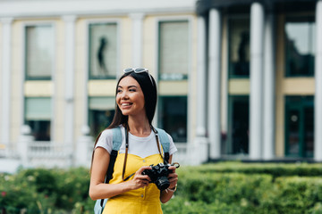 attractive and asian woman with digital camera looking away