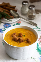 Pumpkin or carrot cream soup with croutons and thyme on a wooden background. Rustic style.