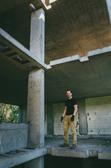 Attractive brutal man in black in an abandoned building. Stalker, lover of extreme adventures.