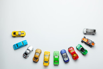 Many colored little toy cars on a gray background.