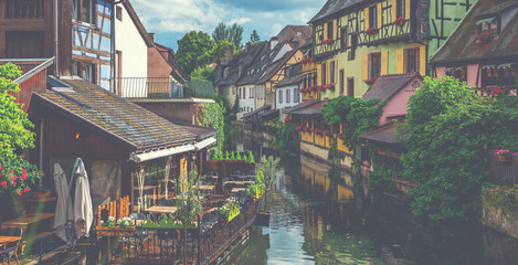 Obraz premium Stately ancient buildings and houses surrounded by many flowers, water canals and greenery. It is called Little Venice. Colmar, Alsace, France.