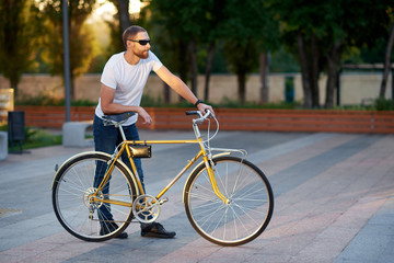 Naklejka premium The red bearded man in casual clothes is cycling on the road in the morning city. Healthy lifestyle concept