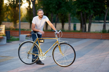 The red bearded man in casual clothes is cycling on the road in the morning city. Healthy lifestyle concept