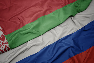 waving colorful flag of russia and national flag of belarus.