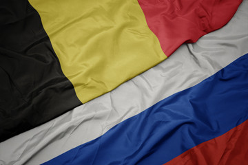 waving colorful flag of russia and national flag of belgium.