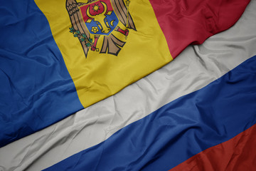 waving colorful flag of russia and national flag of moldova.