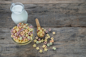 Flat lay composition with healthy cornflakes and milk in bowl on wooden table.