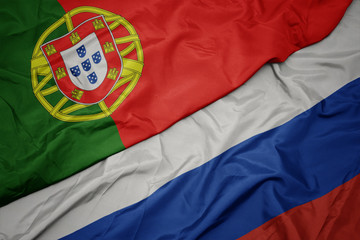 Fototapeta premium waving colorful flag of russia and national flag of portugal.