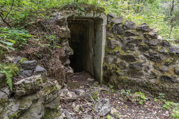 Entrance in bunker or in ancient stone ruins with green moss on masonry stonework