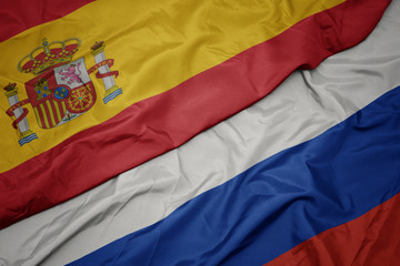 waving colorful flag of russia and national flag of spain.