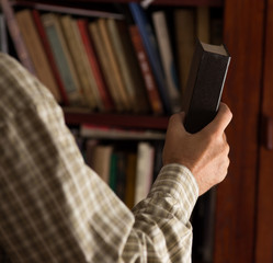 Man putting book on shelf