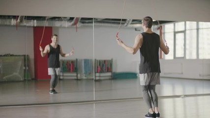 Fitness man training jump exercise on skipping rope in gym club