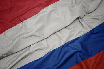 waving colorful flag of russia and national flag of indonesia.