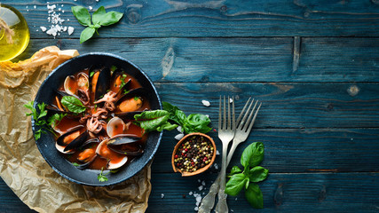 Tomato soup with seafood. Mussels, clams and octopuses. In the old background. Top view. Free copy...