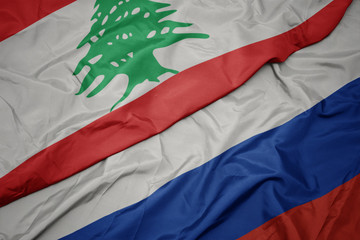 waving colorful flag of russia and national flag of lebanon.