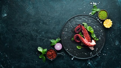 Boiled octopus tentacles on a stone plate. Seafood. Top view. Free copy space.
