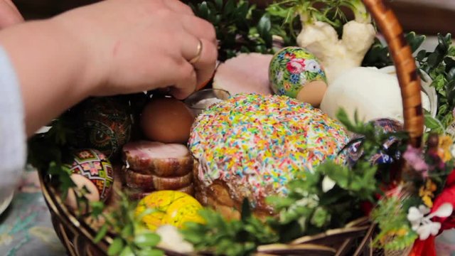 decorate the Easter basket,hands decorate Easter basket with eggs and Easter cake and delicious sausage