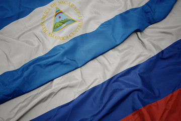 waving colorful flag of russia and national flag of nicaragua.