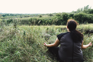 Body positive, yoga, meditation, tranquility, relax. Overweight woman meditating sitting in the...