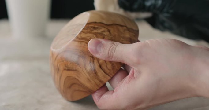 Slow motion woodworker applying oil finish to olive wood bowl