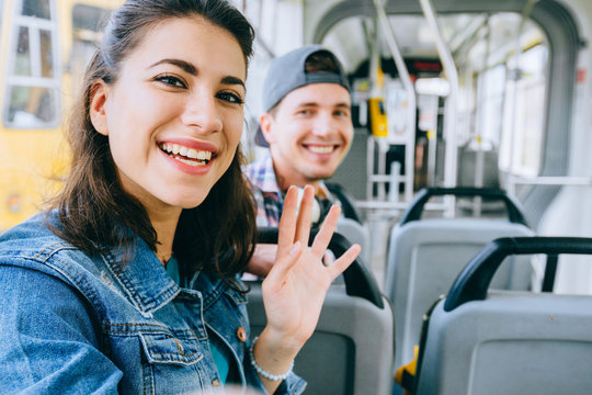 Young smiling multicultural couple talking while sitting in the city bus.