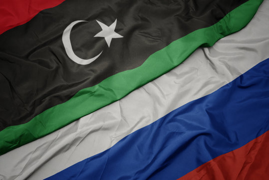 waving colorful flag of russia and national flag of libya.