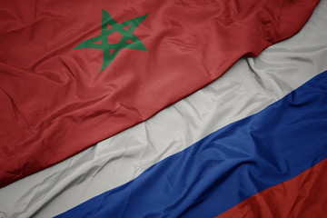 waving colorful flag of russia and national flag of morocco.