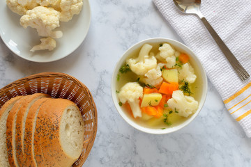 Cauliflower soup with fresh vegetables in a bowl.
