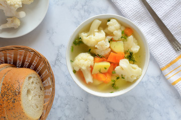Cauliflower soup with fresh vegetables in a bowl.