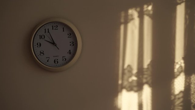 Clock ticking showing ten hours in morning, sunlight from window and shadows on wall. Time deadline concept. Time lapse