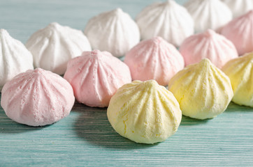 Mini meringues of pastel colors on light blue background
