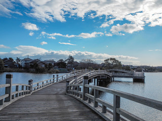 Fototapeta na wymiar Beautiful scene of wooden bridge over the small lake on blue sky with clouds background, copy space,Japan