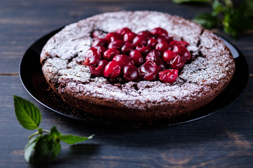 Chocolate clafouti with cherry on a wooden table. French delicious dessert.