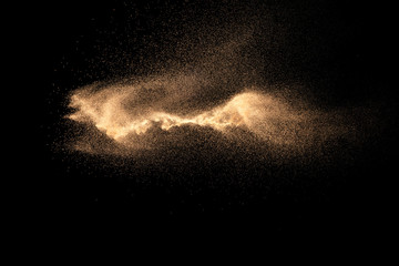 Fototapeta na wymiar Brown particles dust splash on black background. Brown dust explosion.