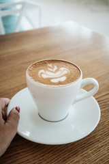 Female hand holds a cup of cappuccino