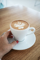 Female hand holds a cup of cappuccino