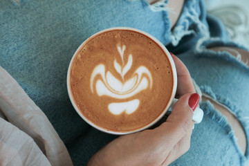 Female hand holds a cup of cappuccino