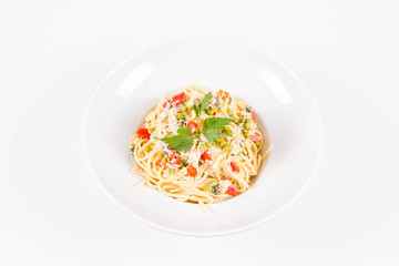 Spaghetti with cream sauce with smoked mackerel, peas ,bell pepper and some parsley on a white plate on a white background