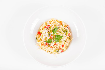 Spaghetti with cream sauce with smoked mackerel, peas ,bell pepper and some parsley on a white plate on a white background