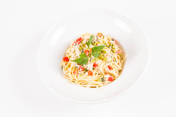 Spaghetti with cream sauce with smoked mackerel, peas ,bell pepper and some parsley on a white plate on a white background