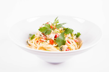 Spaghetti with cream sauce with smoked mackerel, peas ,bell pepper and some parsley on a white plate on a white background