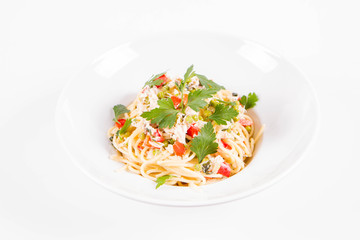 Spaghetti with cream sauce with smoked mackerel, peas ,bell pepper and some parsley on a white plate on a white background