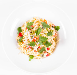 Spaghetti with cream sauce with smoked mackerel, peas ,bell pepper and some parsley on a white plate on a white background