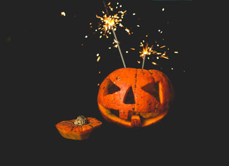 orange pumpkin on black background . cut out the eyes and mouth . the shining light is on.